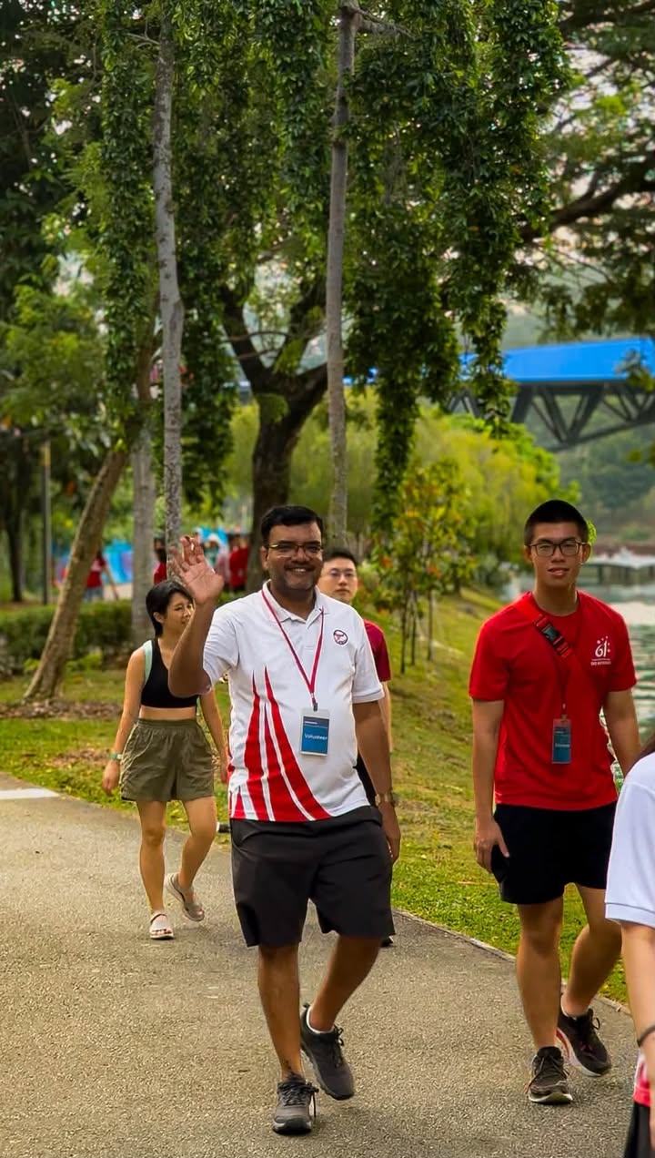 Participants walking in a park-like area near a blue bridge