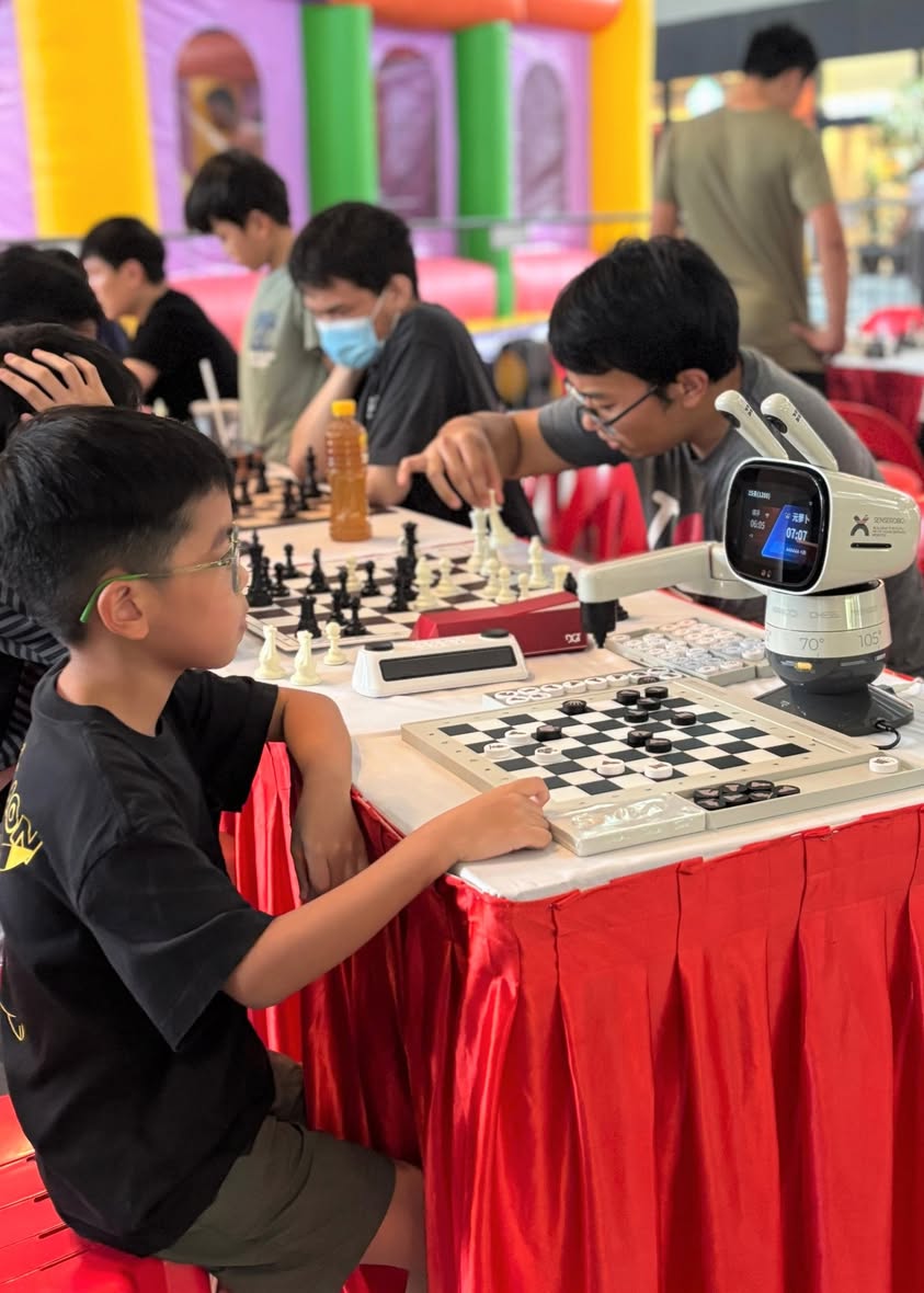 A person challenging a robotic arm in a game of chess.