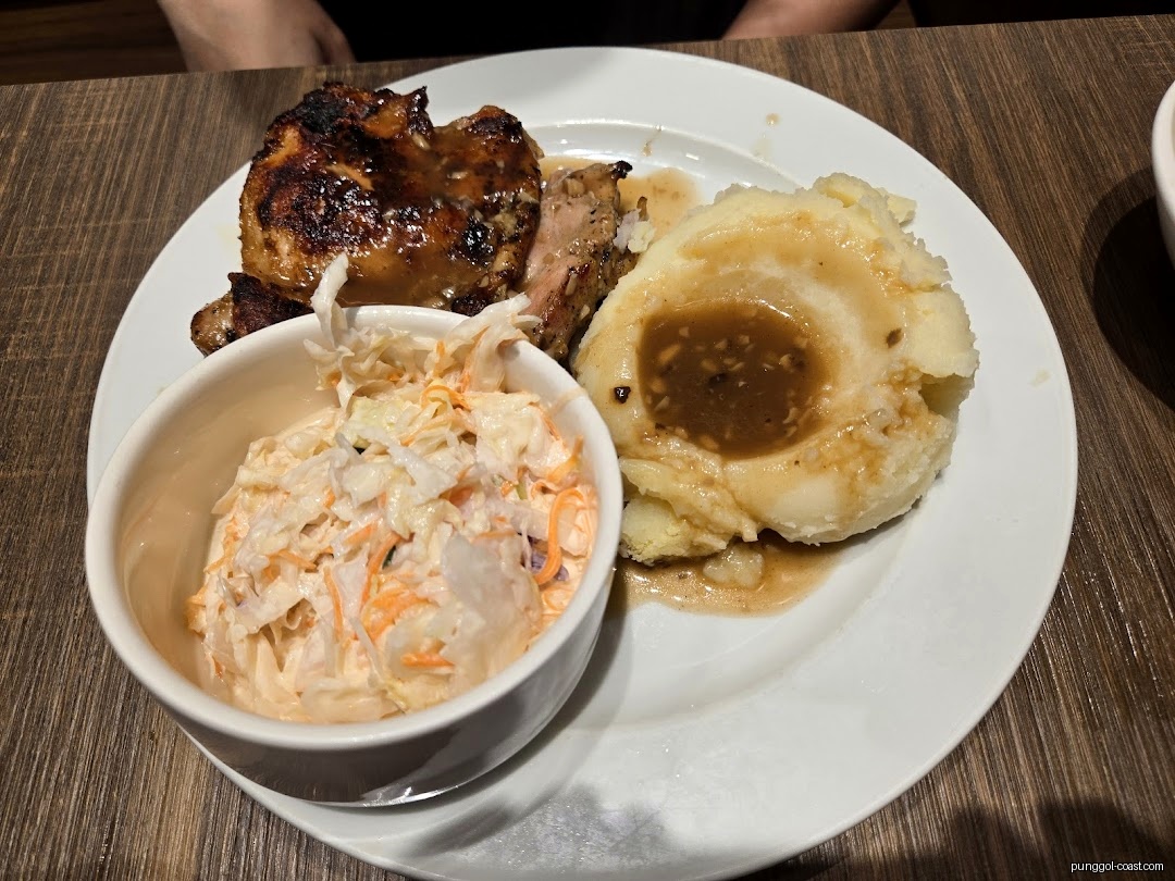 Plate of grilled chicken, mashed potatoes with gravy, and coleslaw.