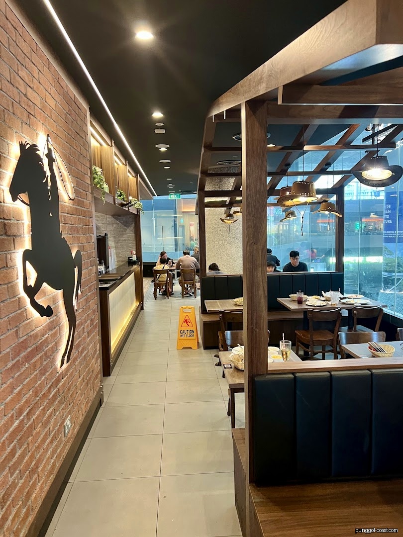 Interior view of a restaurant with dining areas, a brick wall, and customers.