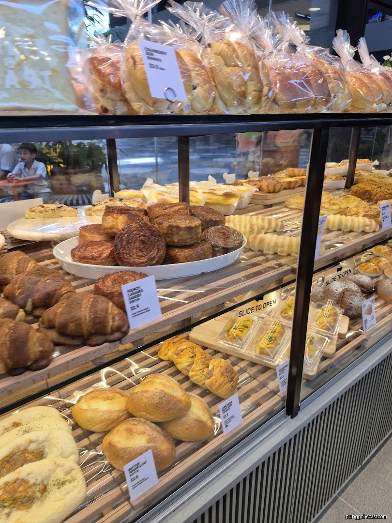A display case filled with various breads and pastries in a bakery.