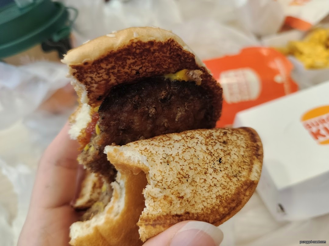 Close-up of a partially eaten burger held in a hand.