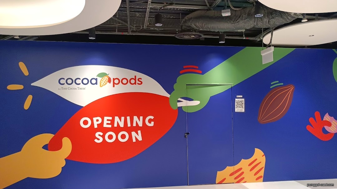 Colorful shop front hoarding for 'Cocoa Pods' with 'Opening Soon' sign.
