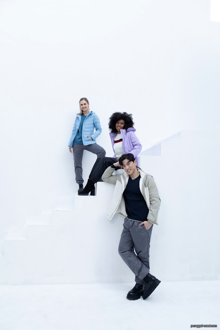Three models wearing winter jackets posing on white stairs.