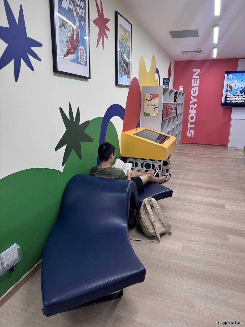 A person reading on a blue lounge chair in a colorful library interior.