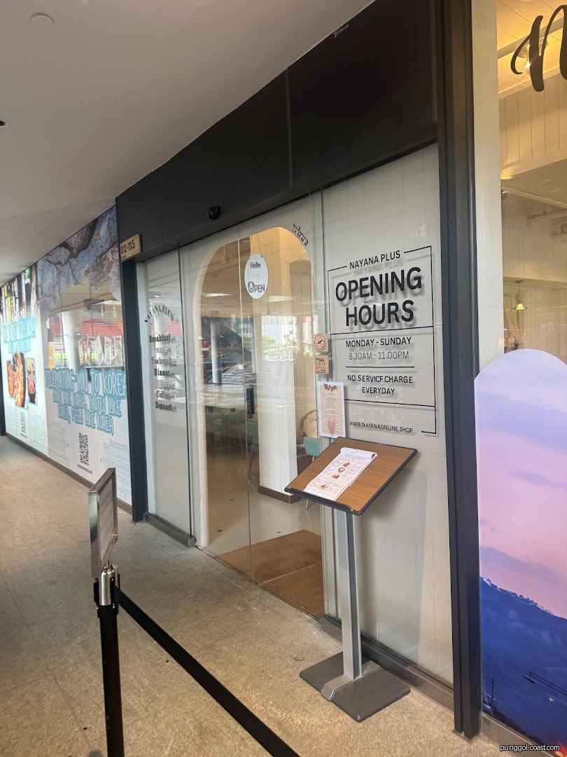 Shop entrance with glass doors, opening hours sign, and a menu stand.