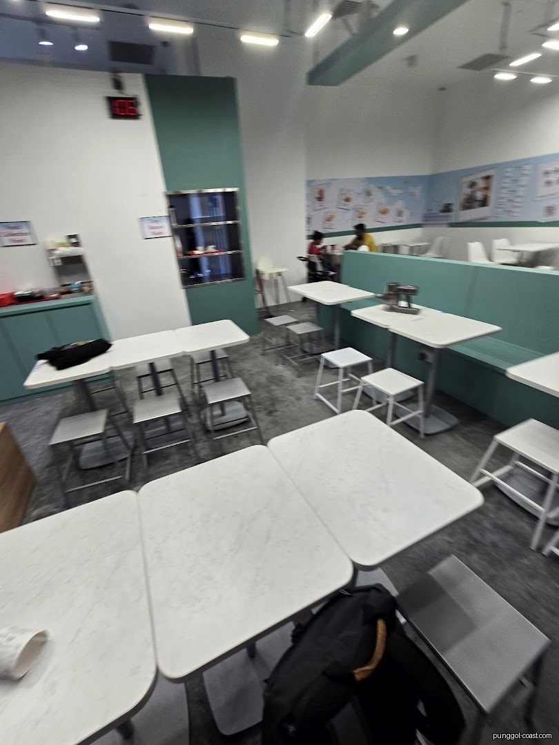 Interior view of a shop's dining area with tables, chairs, and some customers.
