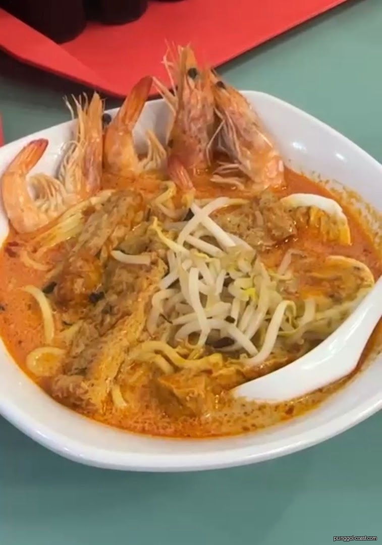 A vibrant bowl of shrimp laksa with noodles and bean sprouts.