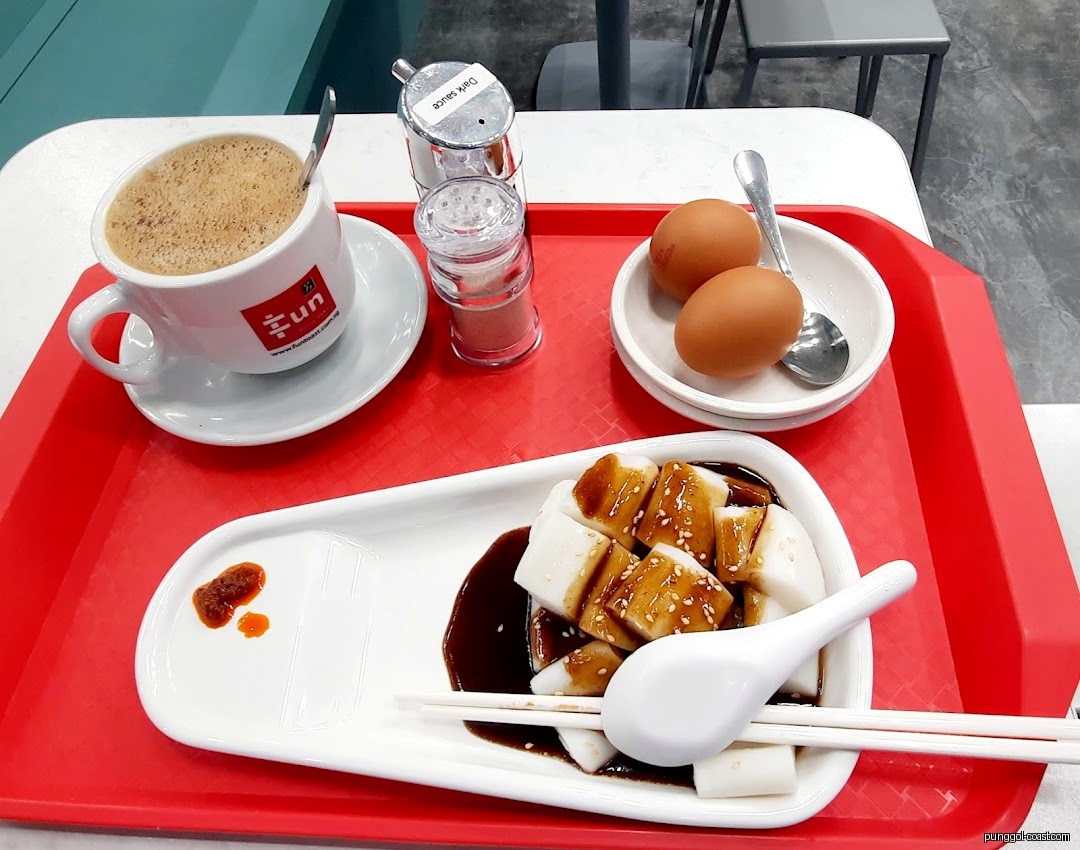 Coffee, eggs, and rice rolls on a red tray at a table.