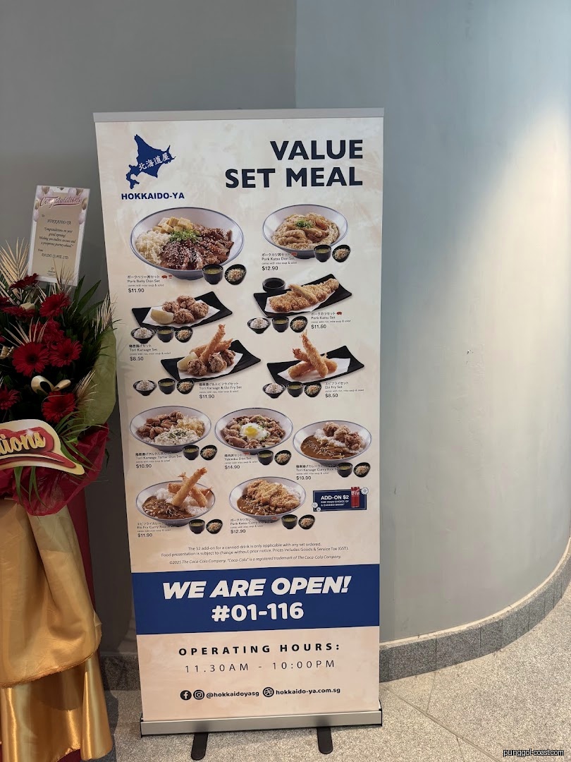 Large banner displays food menu, prices, and operating hours next to flowers.