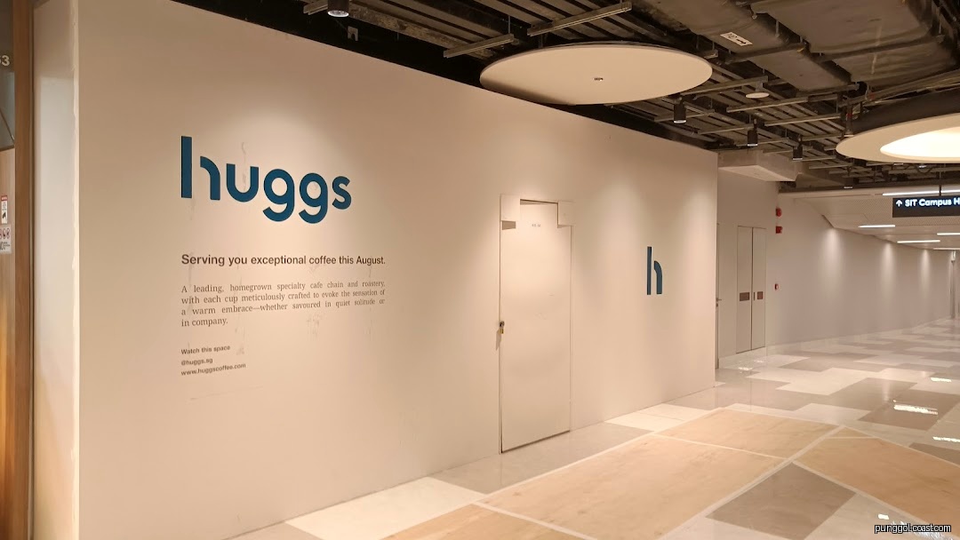 White wall with Huggs Coffee branding, announcing future opening.