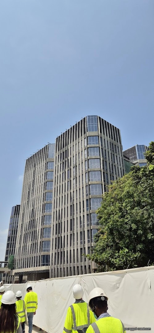 Modern building under construction with workers in foreground under clear sky.