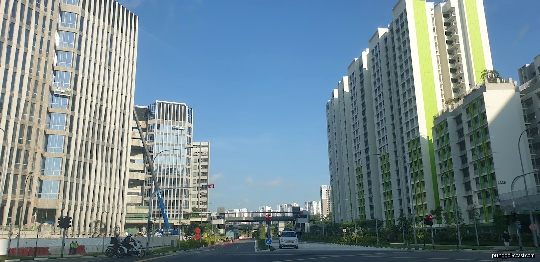 A wide street view with tall modern buildings and a road under a clear sky.