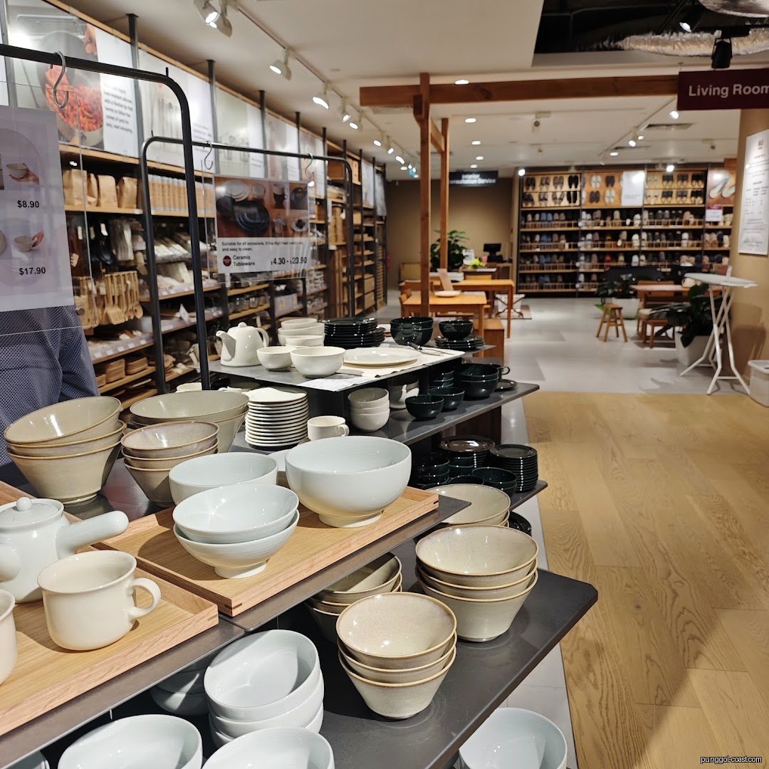 Muji store interior showing shelves of dinnerware and other household goods.