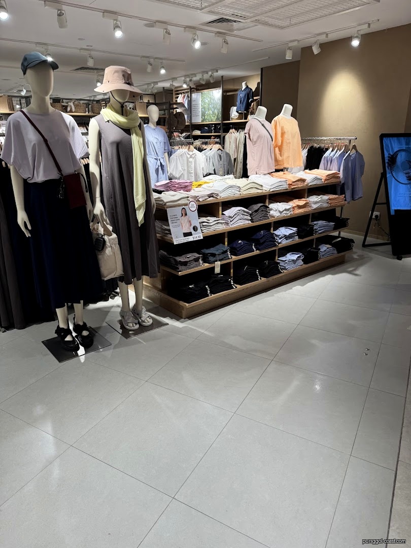 Interior view of a clothing store with mannequins and folded apparel on display.