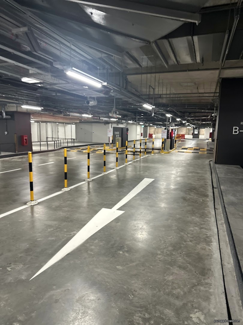Underground parking garage with concrete floor, white arrow, and yellow/black bollards.