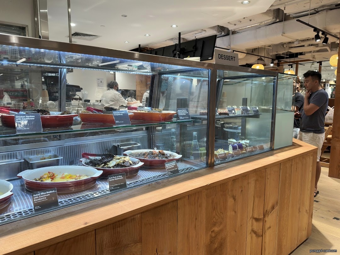 Interior view of a food display counter with prepared dishes and desserts.