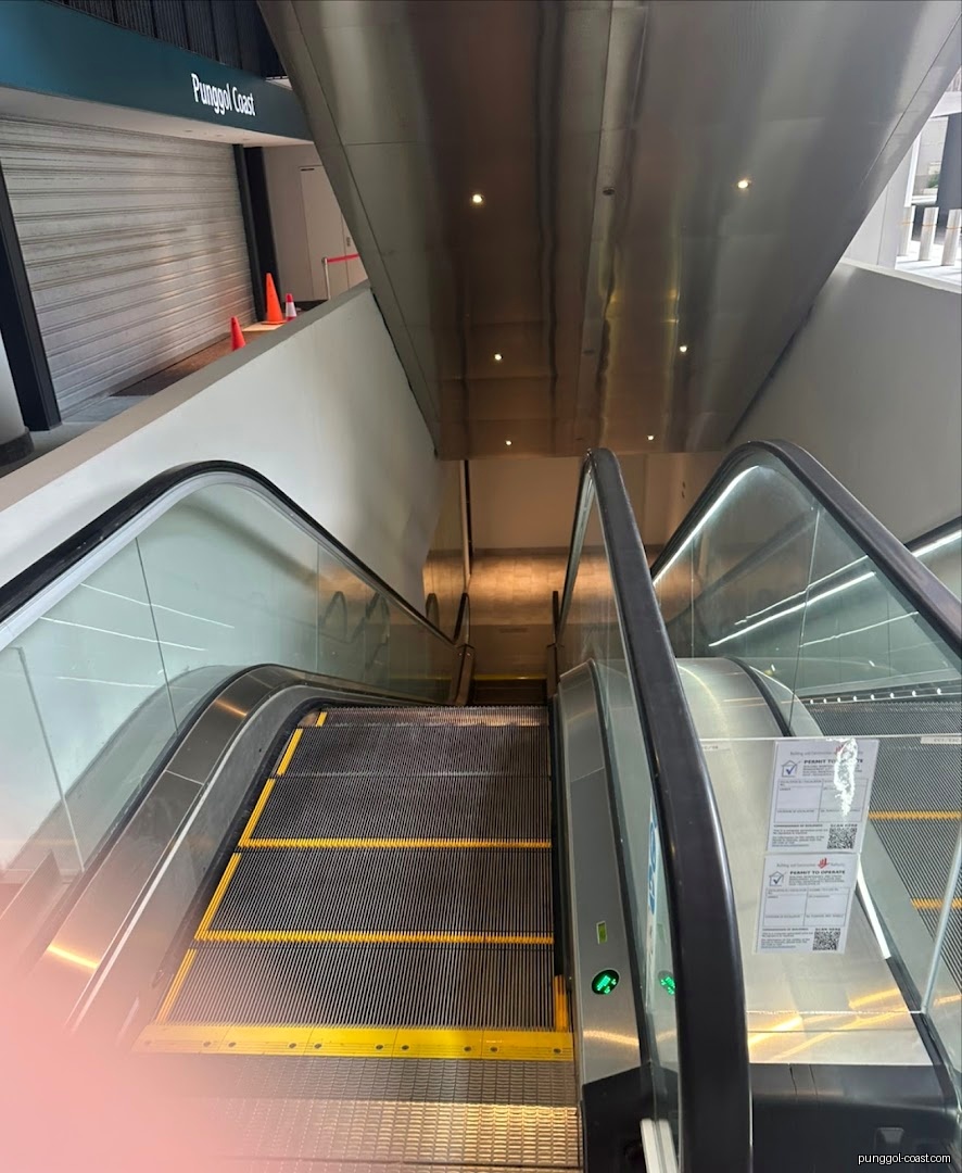 Escalator leading down to a closed entrance with a 'Punggol Coast' sign.