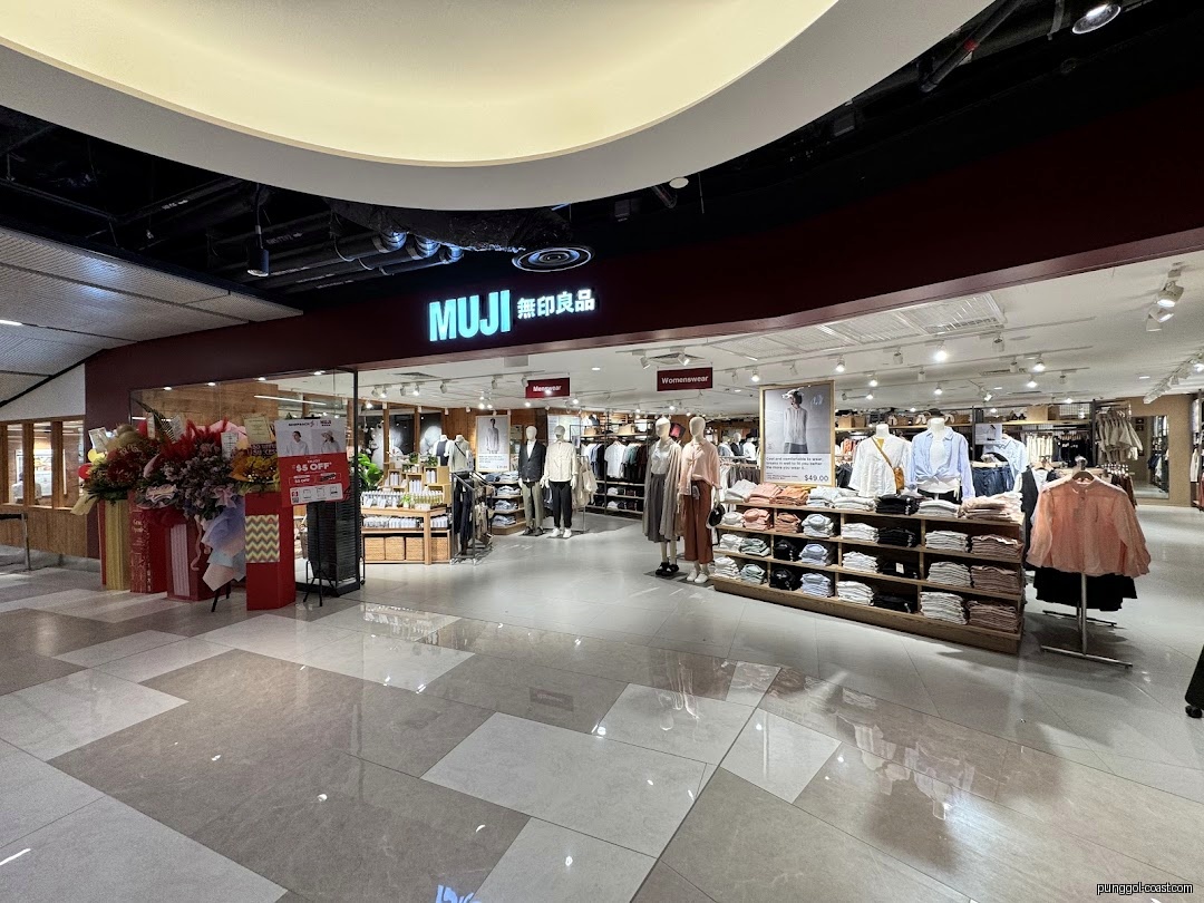 Exterior view of MUJI store entrance with displays and floral arrangements.