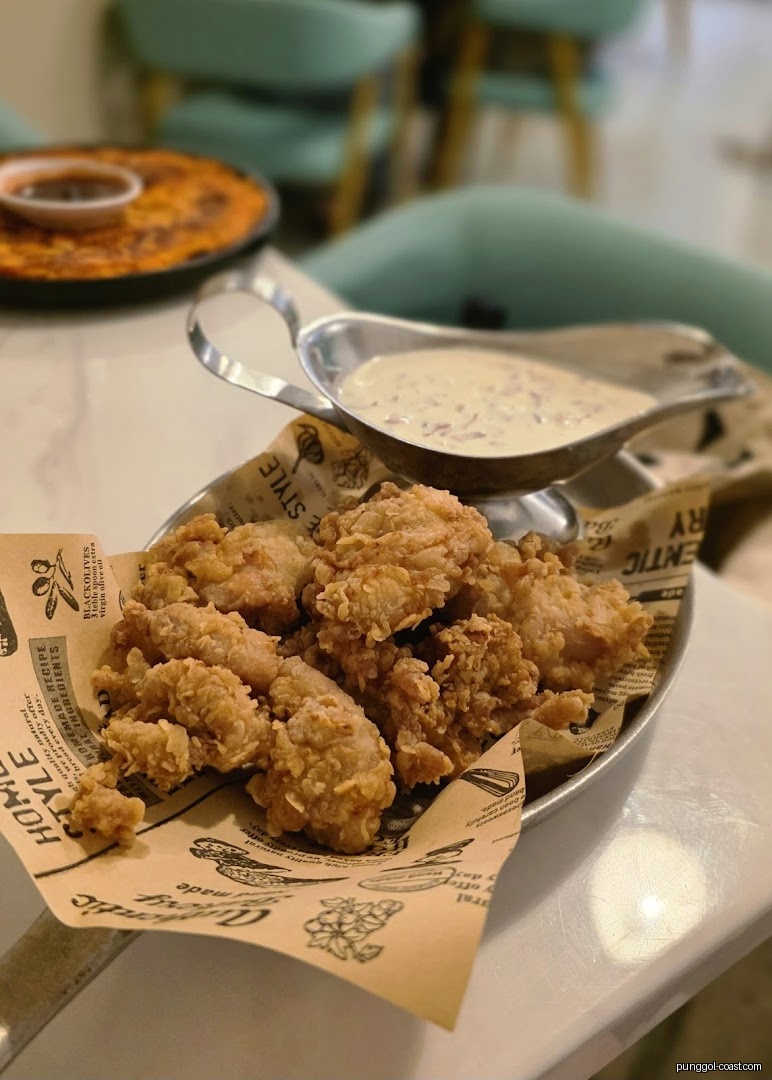 Fried chicken pieces and gravy on a table in a restaurant setting.