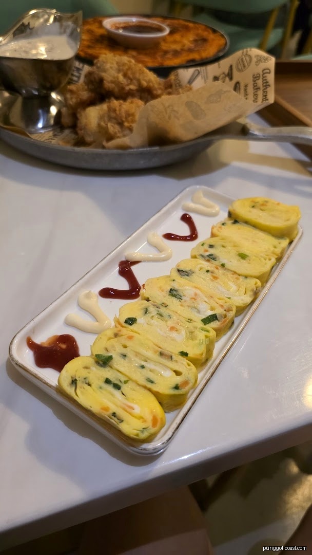 Plates of sliced egg rolls and fried chicken with sauces on a table.
