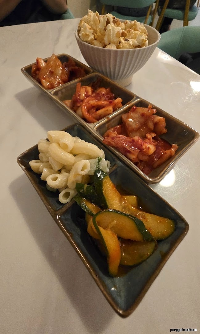 Close-up of a table with popcorn and various Korean side dishes.
