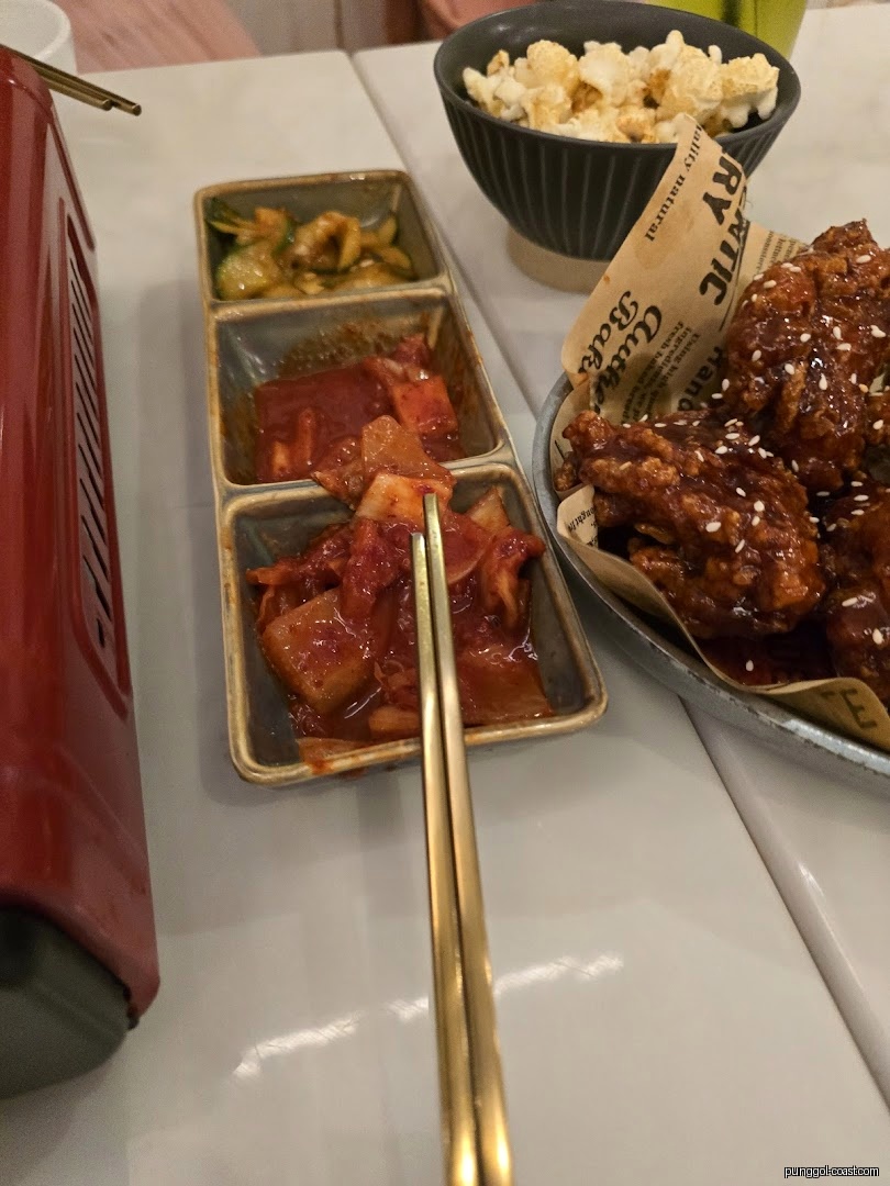 Korean food spread with kimchi, fried chicken, and popcorn on a table.