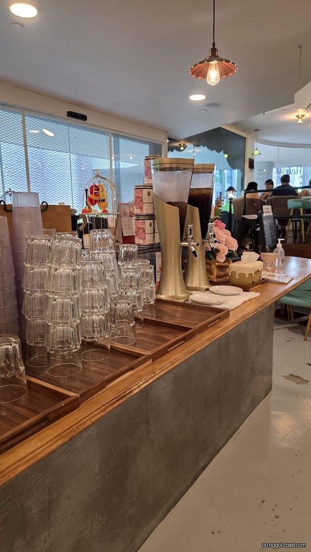 Interior view of a cafe counter with stacked glasses and beverage dispensers.