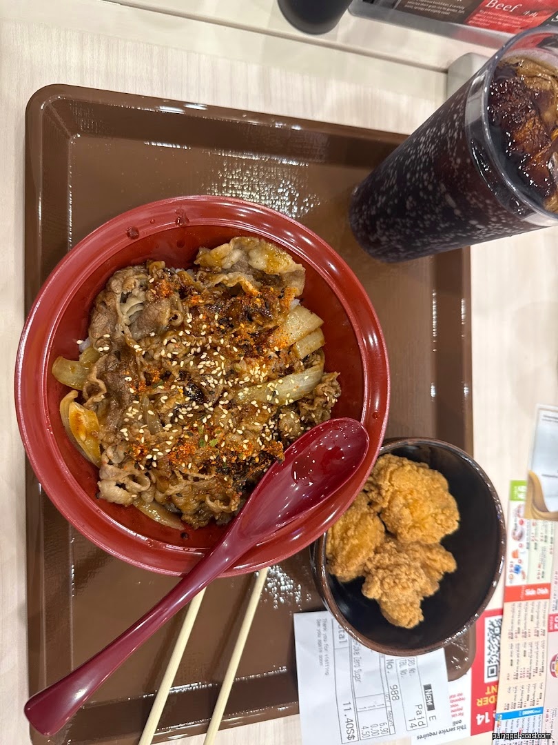 A meal with gyudon, fried chicken, and a drink on a tray.