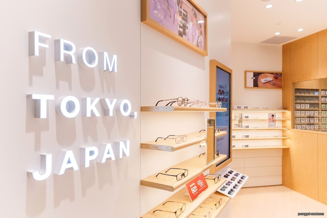 Interior view of an optical shop displaying eyeglasses on shelves and a wall sign.