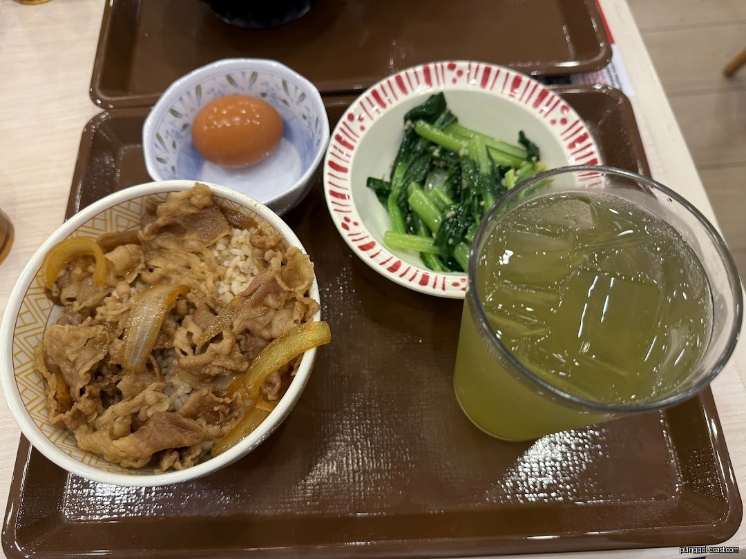 A meal set with gyudon, greens, egg, and iced tea on a tray.