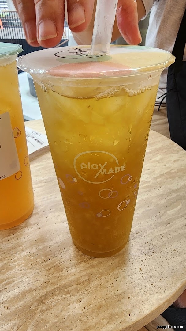 Hand inserting straw into a PlayMade drink on a table.