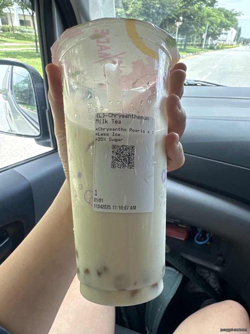 Person holding a bubble tea cup with a label inside a car.
