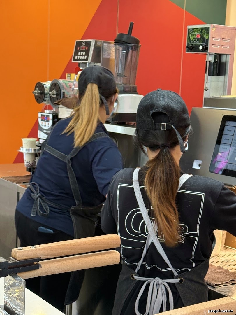 Two staff members working behind a counter with beverage machines.