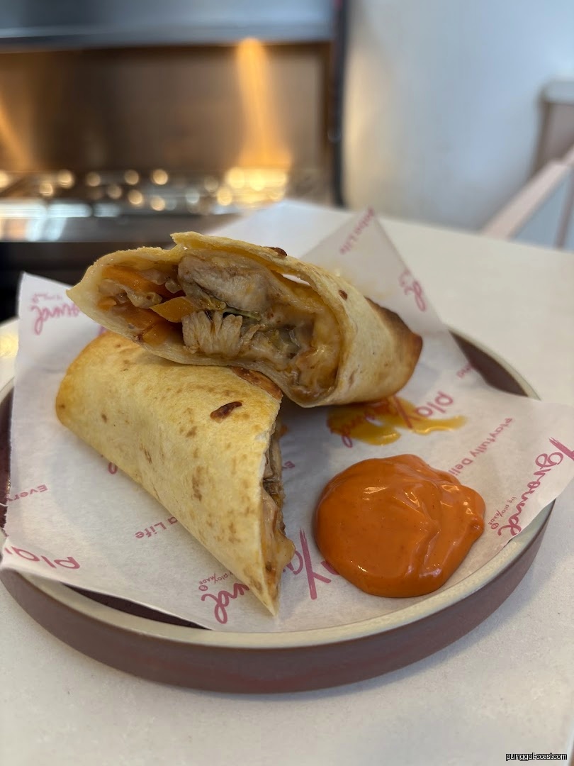 Close-up of a chicken wrap cut in half with sauce on a plate.
