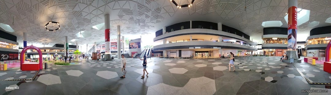 Spacious indoor mall atrium with multiple levels, shops, and people walking around.