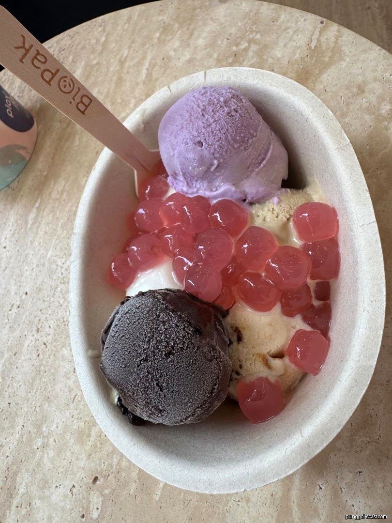 Ice cream with boba pearls in a bowl with a wooden spoon.