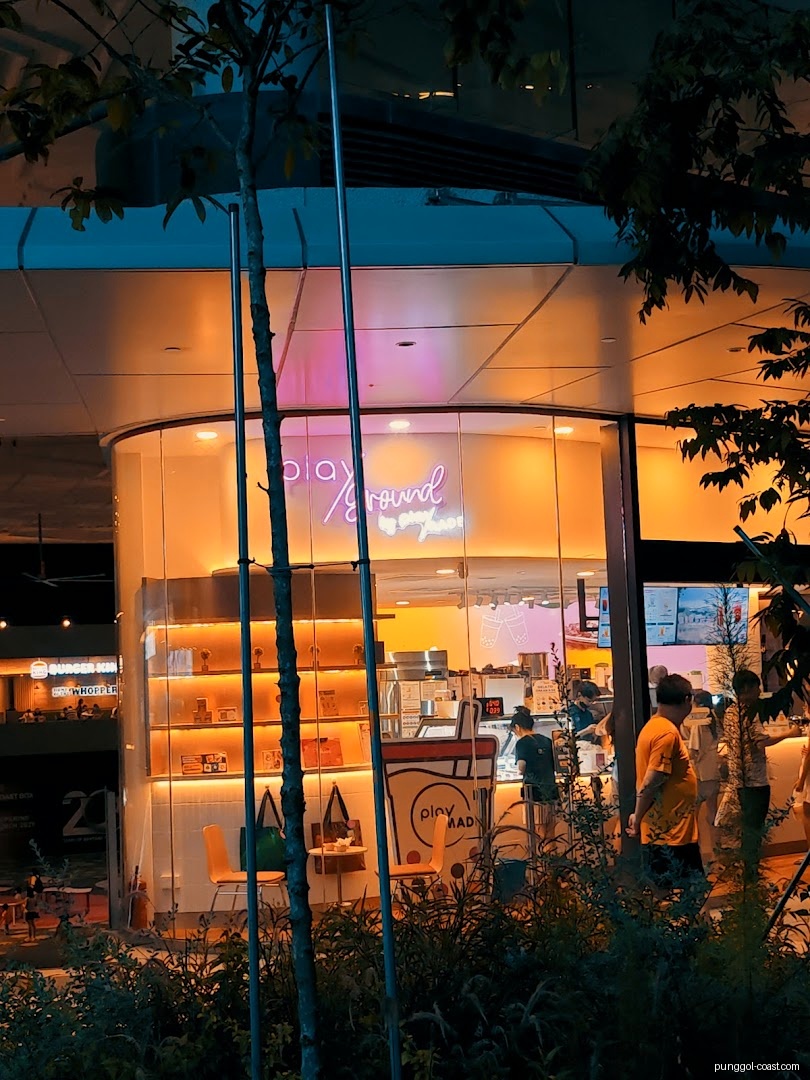 Shop front of 'Playground by PlayMade' at night with neon sign.