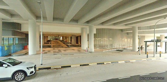 Exterior view of a mall entrance with pillars and a white car.