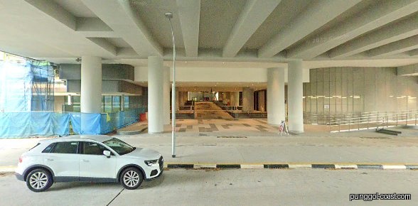 Exterior view of a building entrance with a white car and construction.