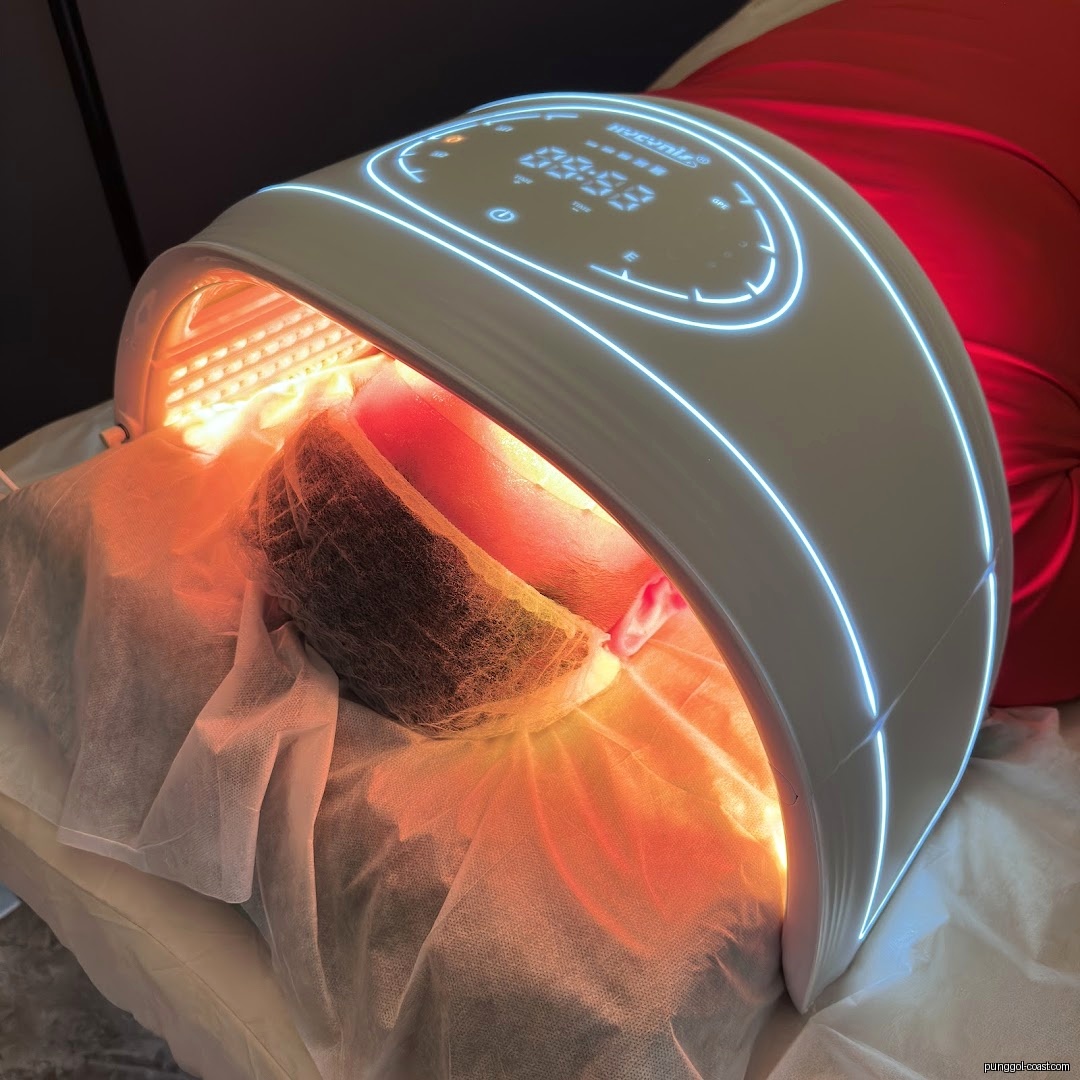 A person's head under a red light therapy machine.
