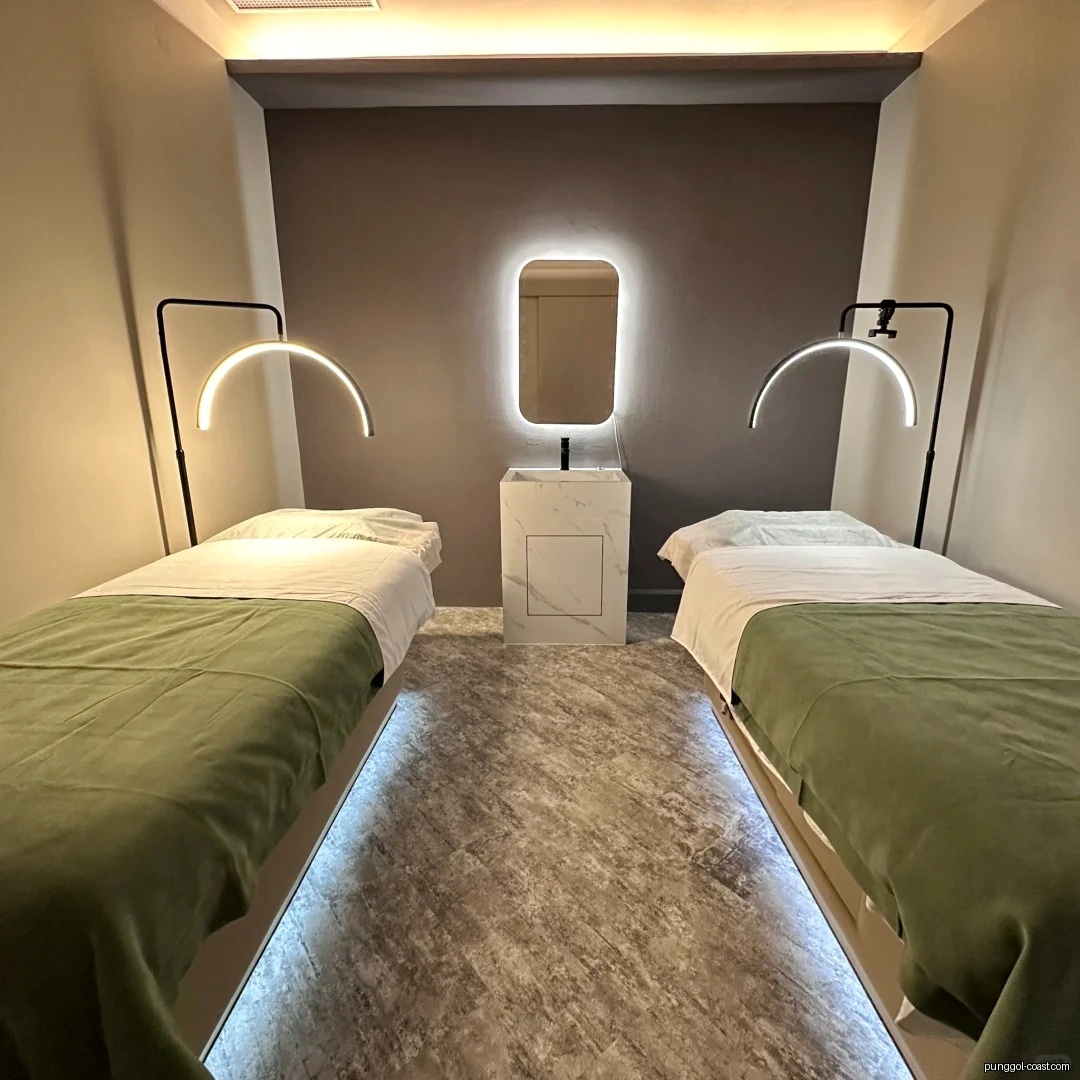 Two treatment beds with lamps and a central sink in a modern room.