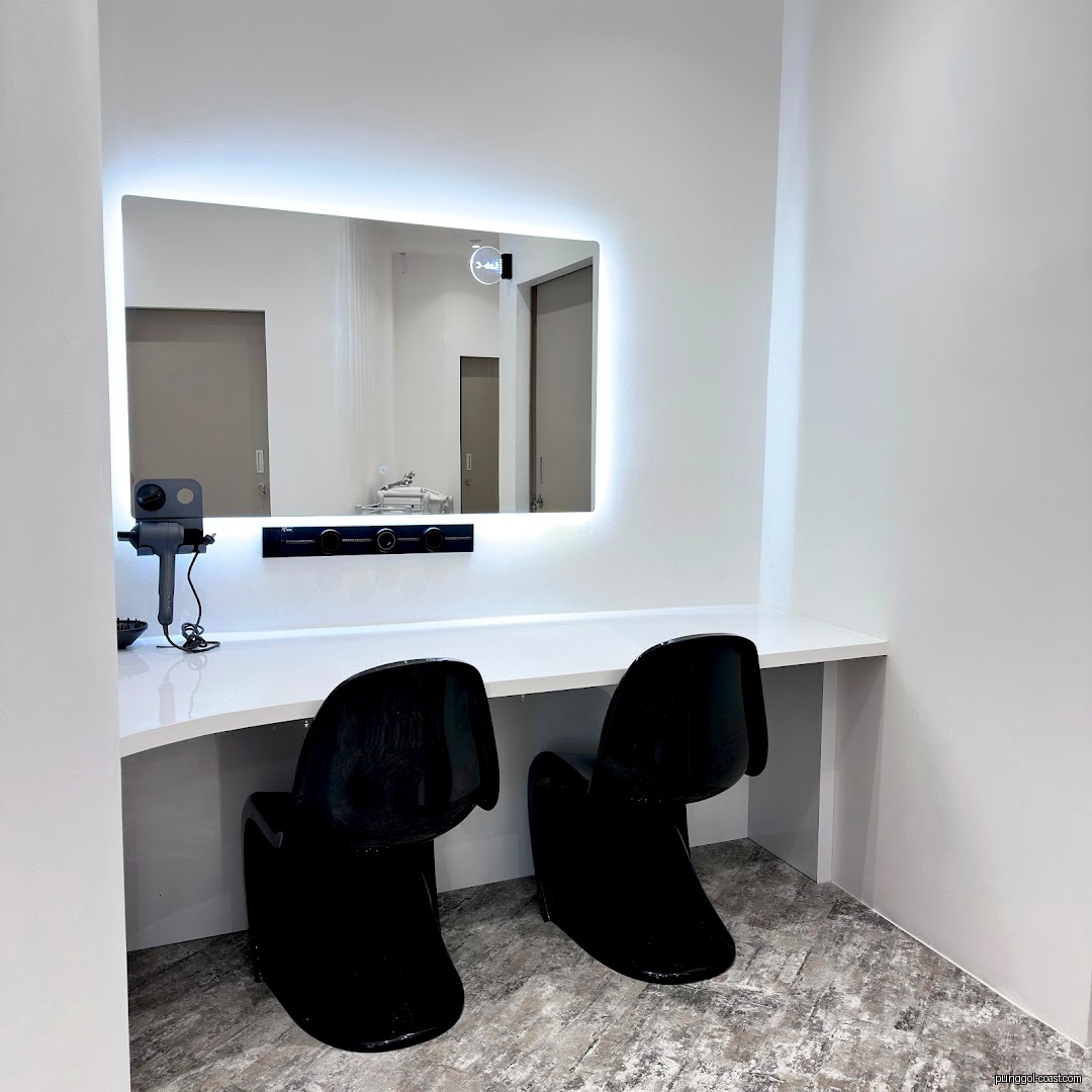 Interior shot of a modern beauty station with illuminated mirror, counter, and two chairs.