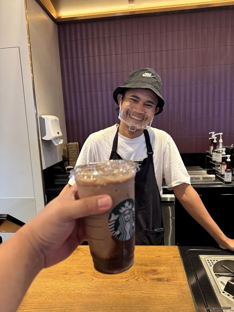 Starbucks employee hands a drink to a customer at the counter.