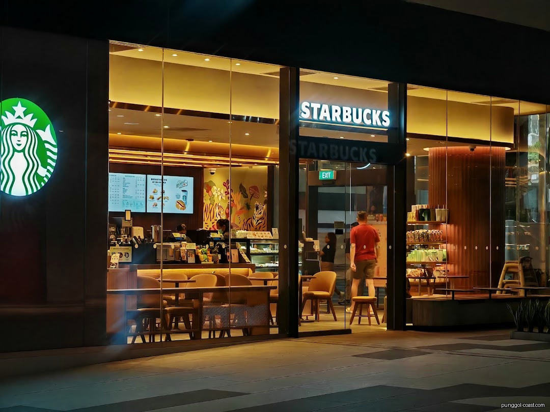 Starbucks shop front at night with illuminated logo and interior.