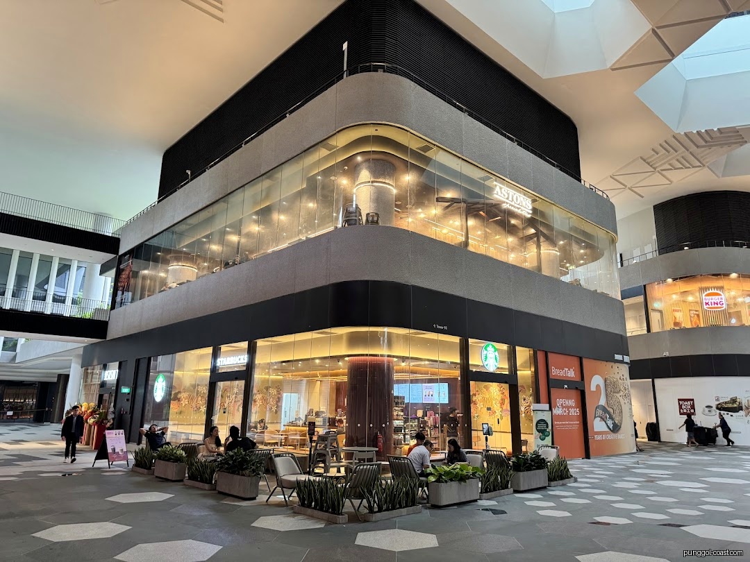 Starbucks shop front with outdoor seating in a modern building.