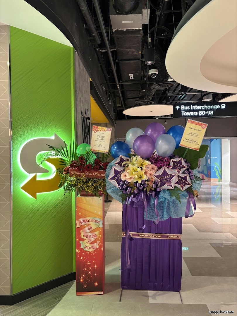 Subway shop entrance decorated with flower stands and balloons for a celebration.
