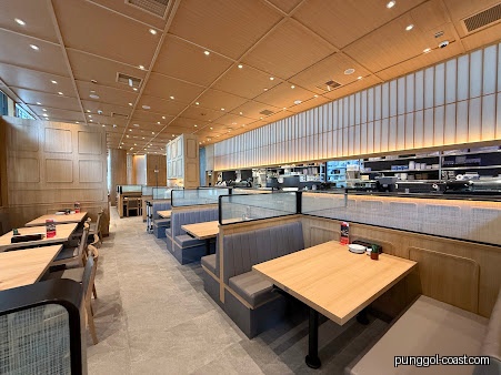 Modern restaurant interior with booths, tables, and a sushi counter.