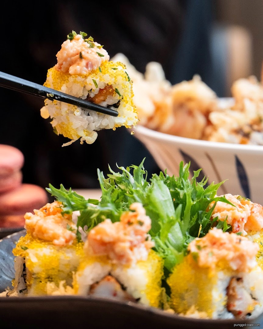 Chopsticks picking up a sushi roll from a plate of sushi.
