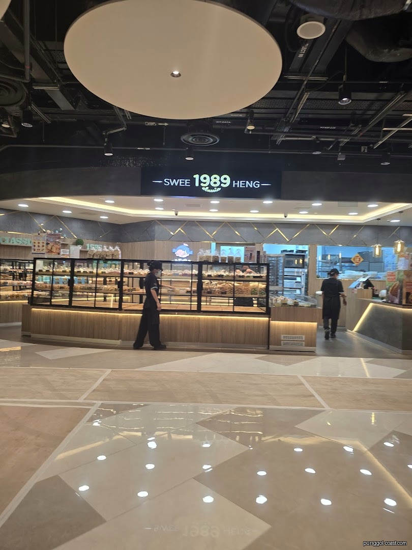 Interior view of a bakery with display cases, products, and staff.